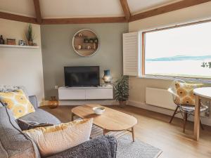 a living room with a couch and a tv and a table at Oversands Cottage in Grange Over Sands