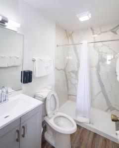 ein weißes Bad mit einem WC und einer Dusche in der Unterkunft Outer Banks Motor Lodge in Kill Devil Hills