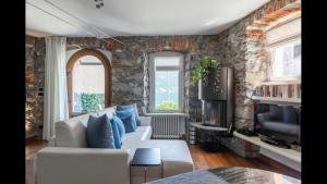 a living room with a white couch and a stone wall at Luxury Lakefront Property in Lezzeno