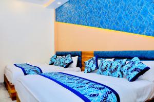 a bedroom with two beds with blue and white pillows at Hotel Lemonade in Amritsar