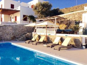 a pool with chairs and umbrellas next to a swimming pool at Seatinview Lodges in Mikonos