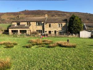 a large stone house with a dog in a field at Simon’s Seat View in Skipton