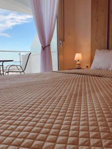 a bedroom with a bed and a chair and a window at Ifigenia Sea View Apartments in Chrysi Ammoudia