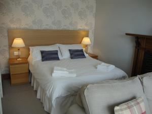 ein Schlafzimmer mit einem großen weißen Bett mit blauen Kissen in der Unterkunft Glanllifon B&B in Criccieth