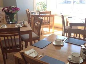 a dining room with wooden tables and chairs and a table and chairsktop at Glanllifon B&B in Criccieth