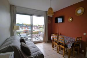 sala de estar con sofá, mesa de comedor y ventana en Appartement au pied de la plage - Balcon - Parking, en Courseulles-sur-Mer