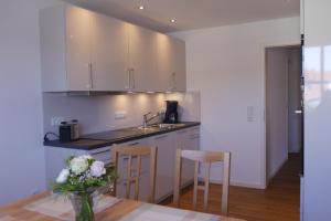 a kitchen with white cabinets and a table with a vase of flowers at Ferienwohnung Rosenberger in Kolitzheim