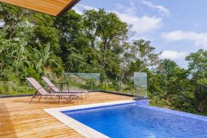 a pool with two chairs and a table on a deck at Casa Nina Santa Teresa in Santa Teresa Beach