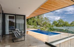 a house with a swimming pool and glass walls at Casa Nina Santa Teresa in Santa Teresa Beach