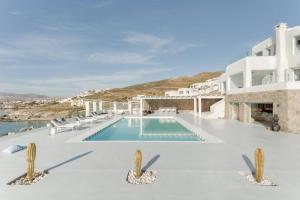 een zwembad met stoelen en een gebouw bij Villa Goddess by Whitelist Mykonos in Agios Ioannis Mykonos