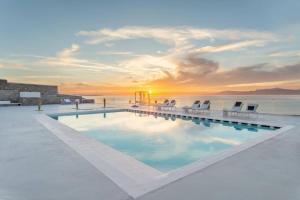 einen Pool mit Sonnenuntergang über dem Wasser in der Unterkunft Villa Goddess by Whitelist Mykonos in Agios Ioannis Mykonos