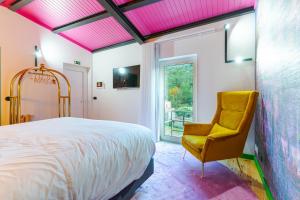 a bedroom with a bed and a yellow chair at Moinho d'Antoninha in Leomil
