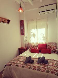 Un dormitorio con una cama con almohadas rojas y una ventana en Apartamentos El Patio Andaluz, en Jerez de la Frontera