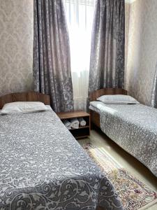 a bedroom with two beds and a window with curtains at AL BARAKA in Borovoye