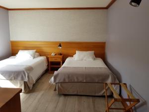 a bedroom with two beds and a night stand with at Hotel Puelche in Puerto Varas
