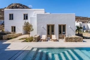 a white house with a swimming pool in front of it at Camarades Mykonos in Ano Mera