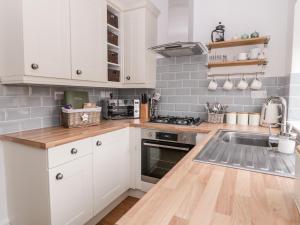 a kitchen with white cabinets and a sink at Ermysted's Cottage in Skipton
