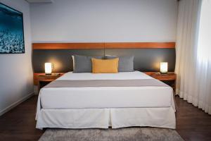 a bedroom with a large white bed with two lamps at Slaviero São Paulo Moema in Sao Paulo