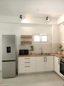 a kitchen with white cabinets and a stainless steel refrigerator at Villa Areti in Lefkimmi