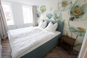 a bedroom with a bed with white sheets and flowers on the wall at PEMATRA Haus Waterkant - FeWo Koje in Travemünde