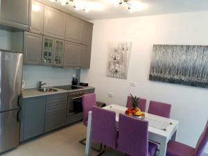 une cuisine avec des chaises violettes, une table et un évier dans l'établissement Orchid SeaView Apartment With Garage Parking, à Zaton