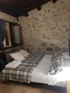 a bed in a room with a stone wall at LA BAITA DEL CONTE in San Massimo