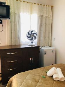 a bedroom with a bed and a window with a fan at Pousada Recanto das Flores in Aiuruoca