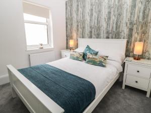 a bedroom with a white bed and a window at Harbour Hideaway in Looe
