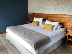 a bedroom with a large bed with two yellow pillows at Hotel Puelche in Puerto Varas