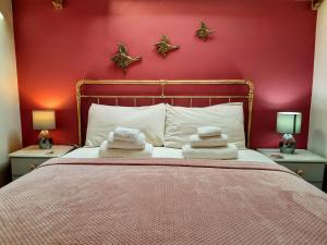 a bedroom with a bed with a red wall at Cosy barn on rural smallholding with alpacas, goats & pigs in Stithians