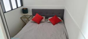 ein Bett mit zwei roten Kissen in einem Zimmer in der Unterkunft Apartament 33 przy latarni in Darłowo