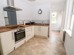 uma cozinha com armários brancos e um relógio na parede em Daisy Cottage em Bideford