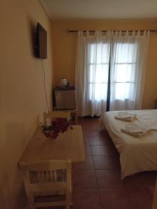 a bedroom with a bed and a table and a window at Kostantaki Studios in Nea Peramos +5 photos