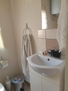 een witte badkamer met een wastafel en een handdoek bij SMALL COTTAGE ASTERIA in Agria