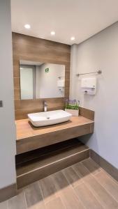 La salle de bains est pourvue d'un lavabo et d'un grand miroir. dans l'établissement HOTEL RILUX Barrancabermeja, à Barrancabermeja