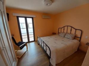 1 dormitorio con paredes de color naranja, 1 cama y 1 silla en Fairways Club, Duplex B22, en San Miguel de Abona
