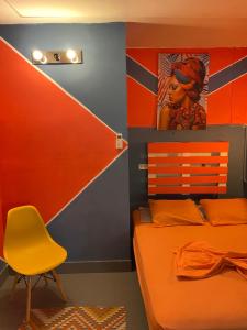 1 dormitorio con 1 cama naranja y 1 silla amarilla en Zebulo Hostel en Panamá