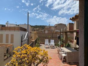 un balcón con sillas y flores en un edificio en NOTARIA-Apartamento y Estudio en casco antiguo, al lado de playa, Rambla y Monasterio, con acceso a terraza ajardinada en Sant Feliu de Guixols