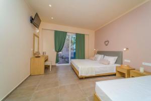 a bedroom with two beds and a window at Amaryllis front beach hotel in Lardos