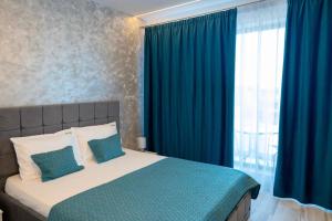 a bedroom with a bed with blue curtains and a window at Bel Air Mamaia Nord Complex - Apartament Delux in Mamaia