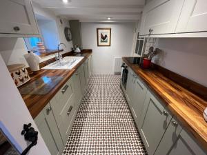 a kitchen with white cabinets and a black and white tile floor at Bwthyn Gynon in Goodwick
