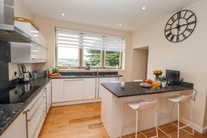 una cocina con armarios blancos y un reloj grande en la pared en Aislaby Hall, en Whitby
