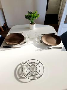 a white table with two plates and glasses on it at Le bord de plage in Bénerville-sur-Mer