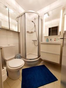 ein Badezimmer mit einer Dusche, einem WC und einem blauen Teppich in der Unterkunft Le bord de plage in Bénerville-sur-Mer
