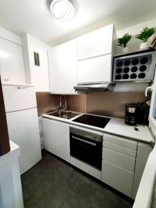 a kitchen with white cabinets and a sink and a stove at Le bord de plage in Bénerville-sur-Mer