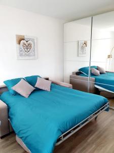 a bedroom with two beds and a mirror at Le bord de plage in Bénerville-sur-Mer