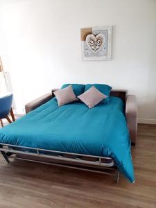 a bed with a blue comforter and pillows on it at Le bord de plage in Bénerville-sur-Mer