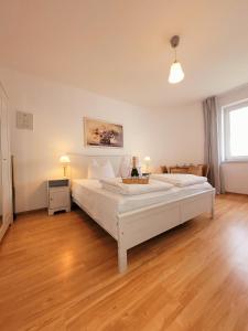 1 dormitorio con 1 cama blanca grande y suelo de madera en IWONA Pokoje Apartamenty en Karwia