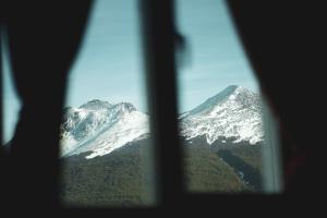 a view of a snow covered mountain through a window at Oshovia Hostel in Ushuaia