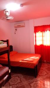 a room with a bed and a window with red curtains at Hostal Casa Yhoanny in Taganga
